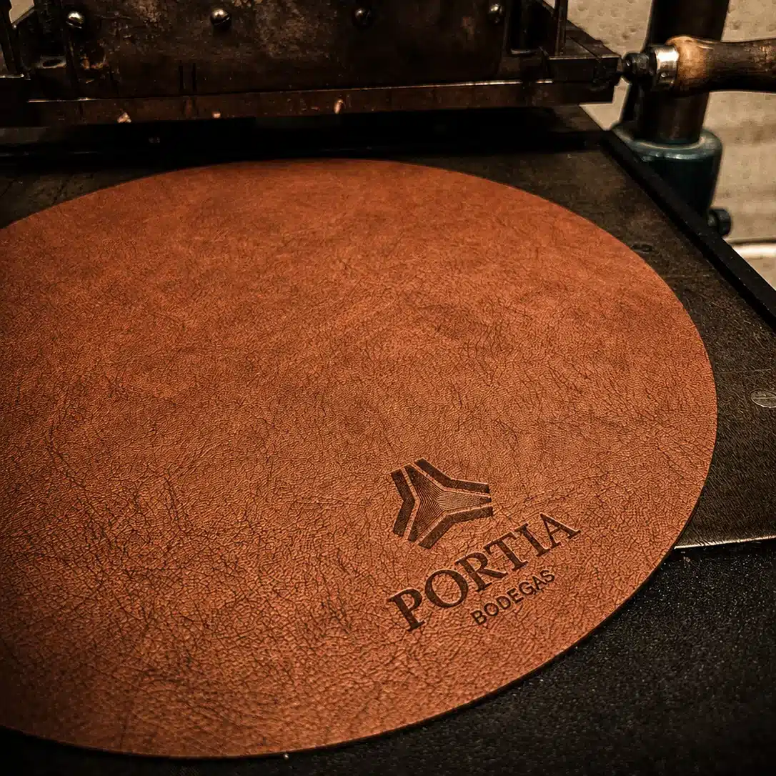 Bajoplatos personalizados de polipiel: así fabricamos los salvamanteles con logotipo de Bodegas Portia 5 Bajoplatos personalizados de polipiel: logotipo de Bodegas Portia grabado en golpe seco, recién fabricado en el taller de Kartia