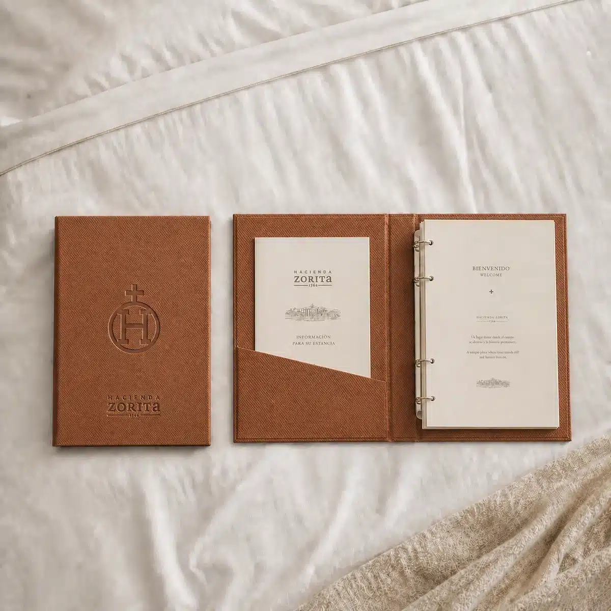 Carpeta de habitación de hotel en polipiel coñac con logo grabado en seco de Hacienda Zorita, con bolsillo interior y anillas para el directorio del huésped, fabricada por Kartia